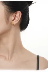 Detail of gold lava-style irregular stud earring with jade-like stone on a model ear