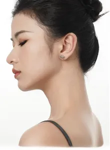 Detail of S925 silver Saturn stud earring with green gemstone on female model ear