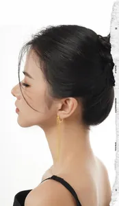 Close-up of elegant gold long tassel drop earrings worn by a model on a white background