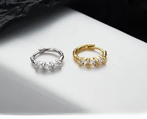 Detailed view of gold and silver irregular lava texture earrings with three inlaid zircons