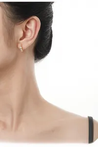Close-up of small irregular textured gold hoop earrings with sparkling inset crystals