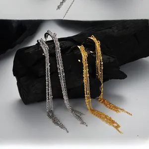 Macro detail of long tassel earrings in silver and gold hanging on black wood stand