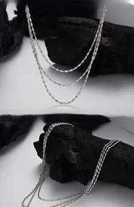 Vue détaillée d'un collier à triple rang d'argent sur une pierre noire minimaliste