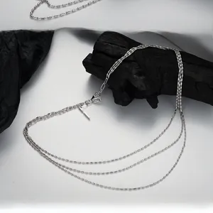 Vue macro d'un collier multicouche argenté montrant des maillons métalliques cylindriques