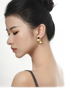 Détail de boucles d'oreilles géométriques dorées à trois couches et émail noir sur modèle