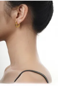 Close-up of gold geometric hexagonal hoop earrings worn by a model in profile