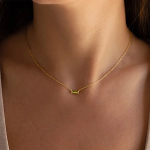 Detail shot of a minimalist gold necklace featuring a rectangular green gemstone pendant
