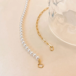 Détail d'un collier double couche avec perles blanches et chaîne en métal doré trombone