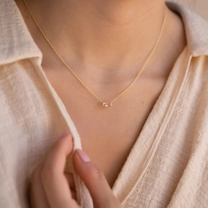 Minimalist gold necklace with a rectangular clear gemstone pendant worn on a model