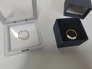 Detailed comparison of gold and silver rings with five freshwater pearls in jewelry boxes