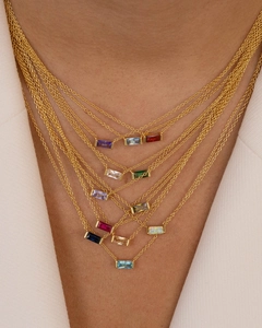 Detail of layered gold necklaces featuring baguette cut colorful birthstone pendants