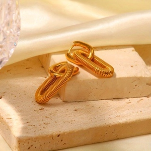 Detail of gold-plated stainless steel hoop earrings with textured spiral chain links