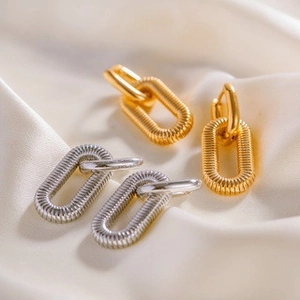 Gold and silver layered link drop earrings on soft silk fabric for a premium aesthetic