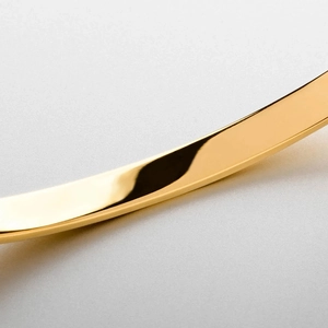 Macro detail of polished gold stainless steel bracelet with mirror finish and smooth edges