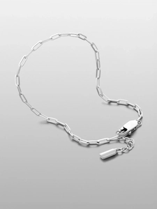 Polished silver paperclip chain bracelet detail showing lobster clasp and tag
