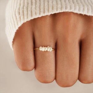 Detail of hand-threaded freshwater pearl ring with gold accents on model's hand