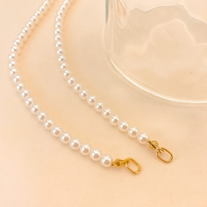 Détail macro de perles blanches lustrées avec fermoirs dorés élégants sur fond pêche