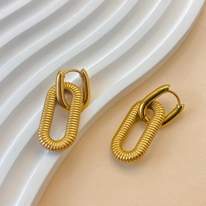 Detailed macro shot of gold-plated chain earrings with textured oval pendants