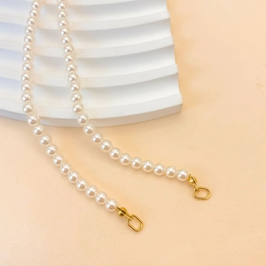 Collier élégant en perles blanches brillantes avec fermoir doré sur fond corail doux