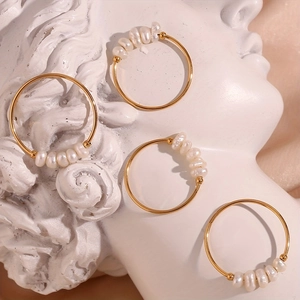 Detail of four gold thin hoop earrings with natural freshwater pearls on a sculpture