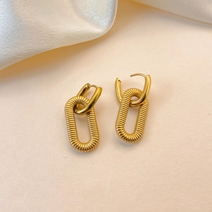 Macro detail of gold plated stainless steel chain earrings on elegant silk background