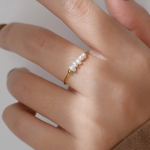Detailed macro view of five natural freshwater pearls set on a slim gold stainless steel ring