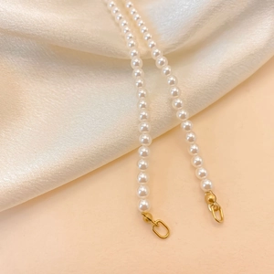 Détail de perles blanches sur une chaîne avec un fermoir en métal doré poli brillant
