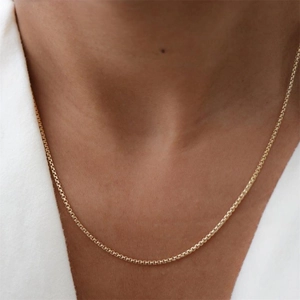 Detailed view of a gold-plated stainless steel box chain necklace on model neck
