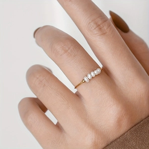 Detailed view of a gold-finish minimalist ring featuring five elegant small white pearls