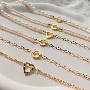 Détail macro du collier en perles baroques et chaîne trombone dorée avec fermoir cœur S925