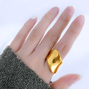 Nahaufnahme eines unregelmäßigen Wellenrings aus goldenem Titanstahl an der Hand