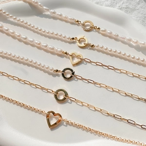 Détail du collier de perles baroques avec fermoir cœur doré et cristaux sur plateau blanc