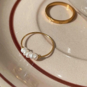 Detail shot of a gold minimalist ring featuring five white natural freshwater pearls
