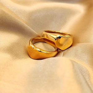 Detail of two gold-plated heart signet rings resting on luxurious warm silk fabric