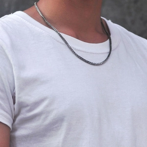 Gros plan d'un collier chaîne vénitienne minimaliste en argent sur un mannequin homme