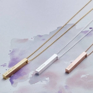 Macro detail of custom engraved bar necklaces in gold, silver and rose gold finishes