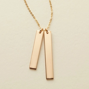 Macro detail of high-polish gold bar pendants on a minimalist fine cable chain necklace