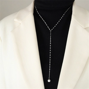 Close-up of a silver Y-shaped twist chain necklace with a round white pearl pendant detail