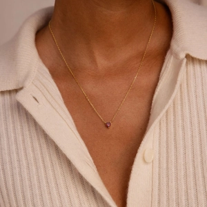 Collier élégant en chaîne dorée avec pendentif cœur rouge porté par un mannequin