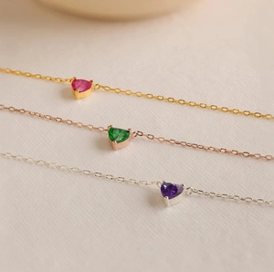 Vue détaillée de pendentifs pierre de naissance en cœur sur fines chaînes or et argent