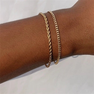 Set of two gold stainless steel bracelets with rope and cuban chain on a model's wrist