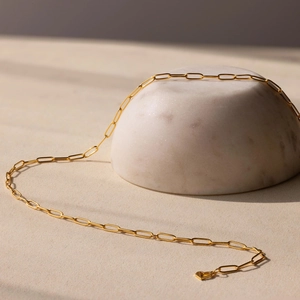 Detail of a 14k gold plated paperclip chain necklace with a delicate heart pendant