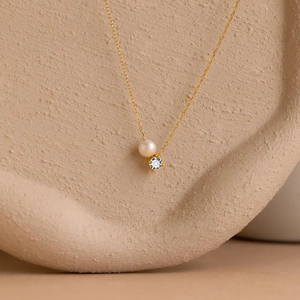 Elegant gold chain necklace with a round white pearl and sparkling zircon pendant