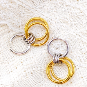 Detail of mixed-metal multi-hoop earrings featuring gold and silver rings on white lace