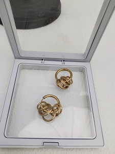 Détail de boucles d'oreilles dorées multi-anneaux dans leur boîte de présentation blanche