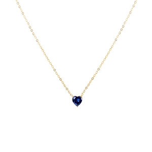 Détail du pendentif avec gemme bleue en forme de cœur sur chaîne en acier doré
