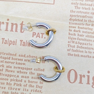 Detailed macro view of silver C-shaped hoop earrings with gold ring accent and silicone backs