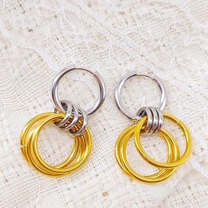 Detailed top view of two-tone stainless steel hoop earrings on white lace background