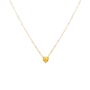 Détail d'un collier en cœur doré avec une pierre précieuse jaune sertie par trois griffes