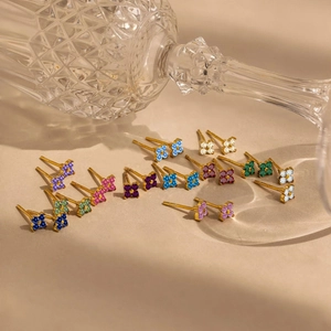 Bunte Zirkon-Blumen-Ohrstecker mit Goldbeschichtung auf minimalistischem beigem Hintergrund